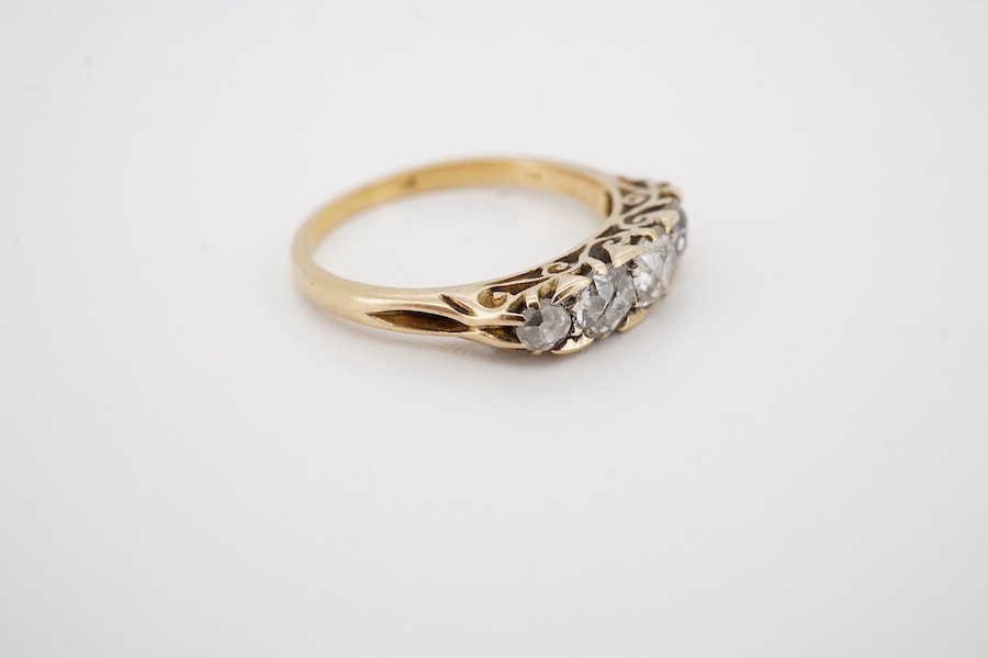 An early to mid 20th century yellow metal and graduated five stone diamond set half hoop ring, size L, gross weight 2.2 grams. Condition - poor to fair